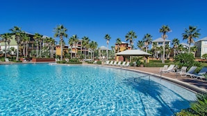 A swimming pool with lounge chairs and palm trees.