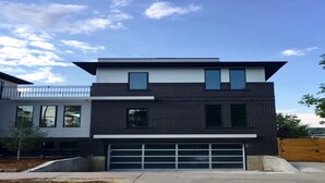 Een modern huis met twee verdiepingen, een garage, grote ramen en een balkon.