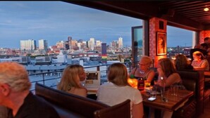 Een restaurant met uitzicht op de skyline van de stad, een terras en een modern architectonisch ontwerp.