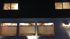 A two-story building with two illuminated windows on the upper floor and three on the lower floor. - B&B Neagari (Nomi)