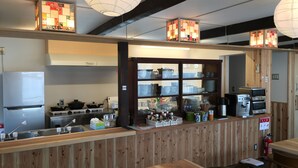A restaurant interior with wooden paneling, a kitchen area with appliances, and hanging paper lanterns. - B&B Neagari (Nomi)