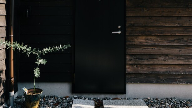A traditional Japanese house with a black door, a small garden with stepping stones, and a potted plant. - B&B Neagari (Nomi)