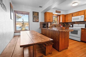 A kitchen with wooden cabinets, a granite countertop, a built-in oven, and a window overlooking a lake.