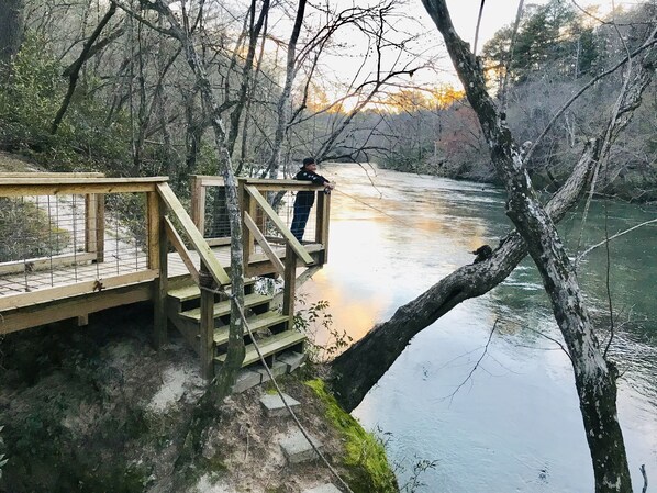 A wooden bridge over a river with a person standing on it.