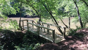 Un pont en bois enjambant une rivière, le tout entouré d’une végétation luxuriante.