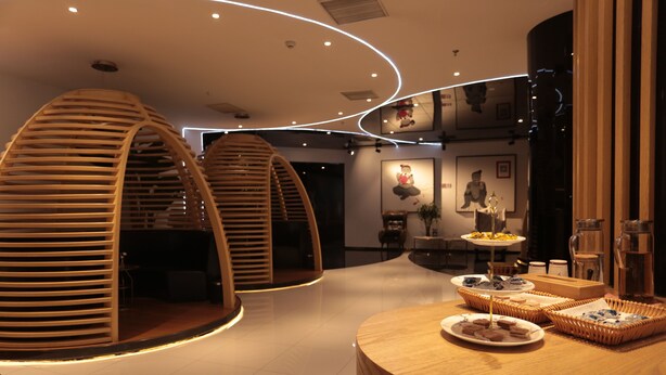 A modern hotel lobby with a circular seating area, a reception desk, and a wall with framed artwork.