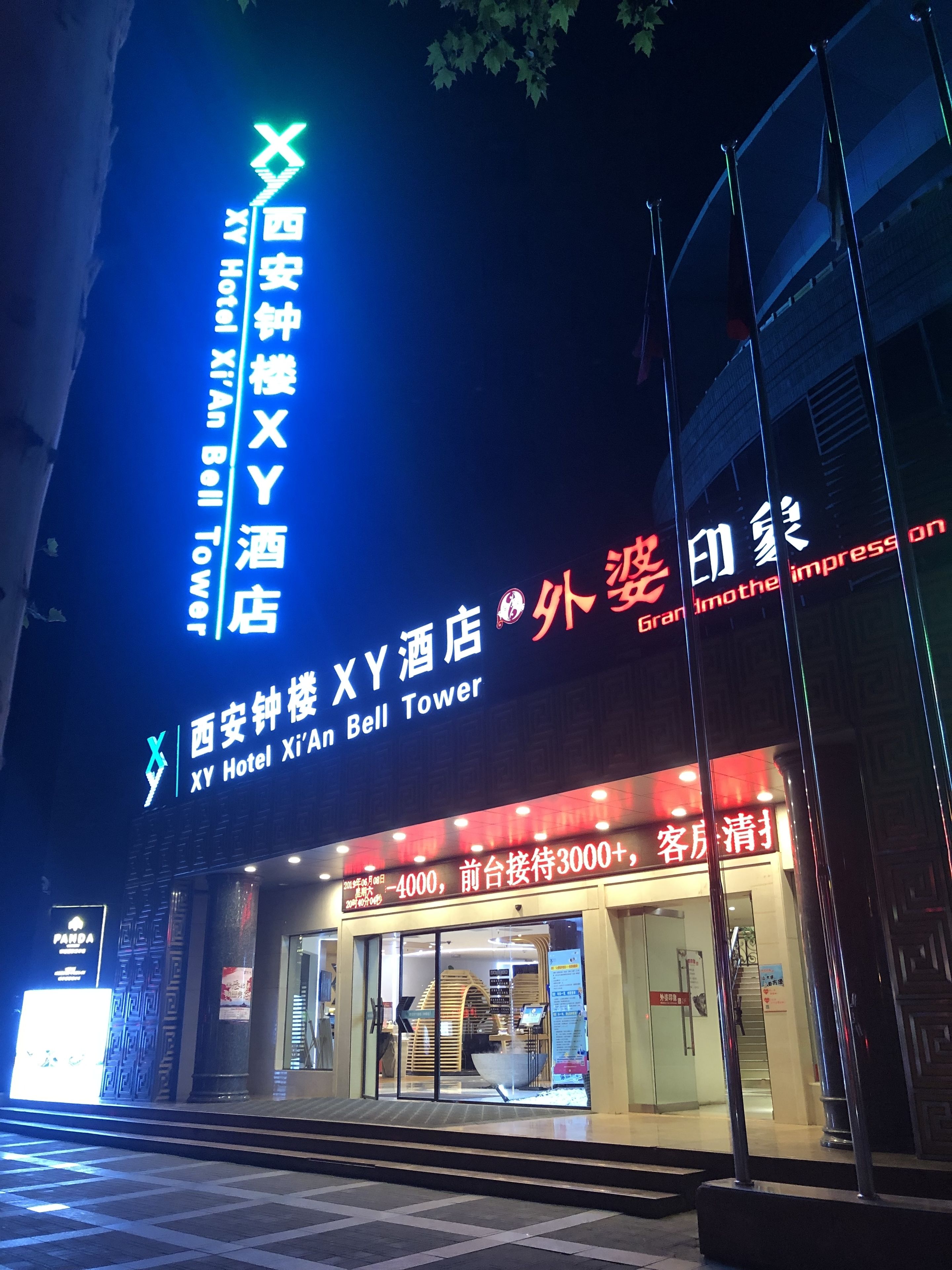 L’extérieur de l’hôtel XY, situé près de la tour de l’horloge de Xi’an, se distingue par une enseigne lumineuse bien visible, indiquant le nom de l’hôtel et son emplacement.