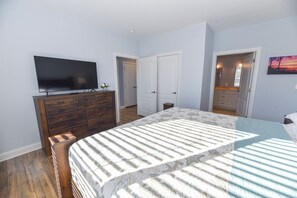 Camera da letto con un letto, una cassettiera, una TV e una porta che dà su un bagno.