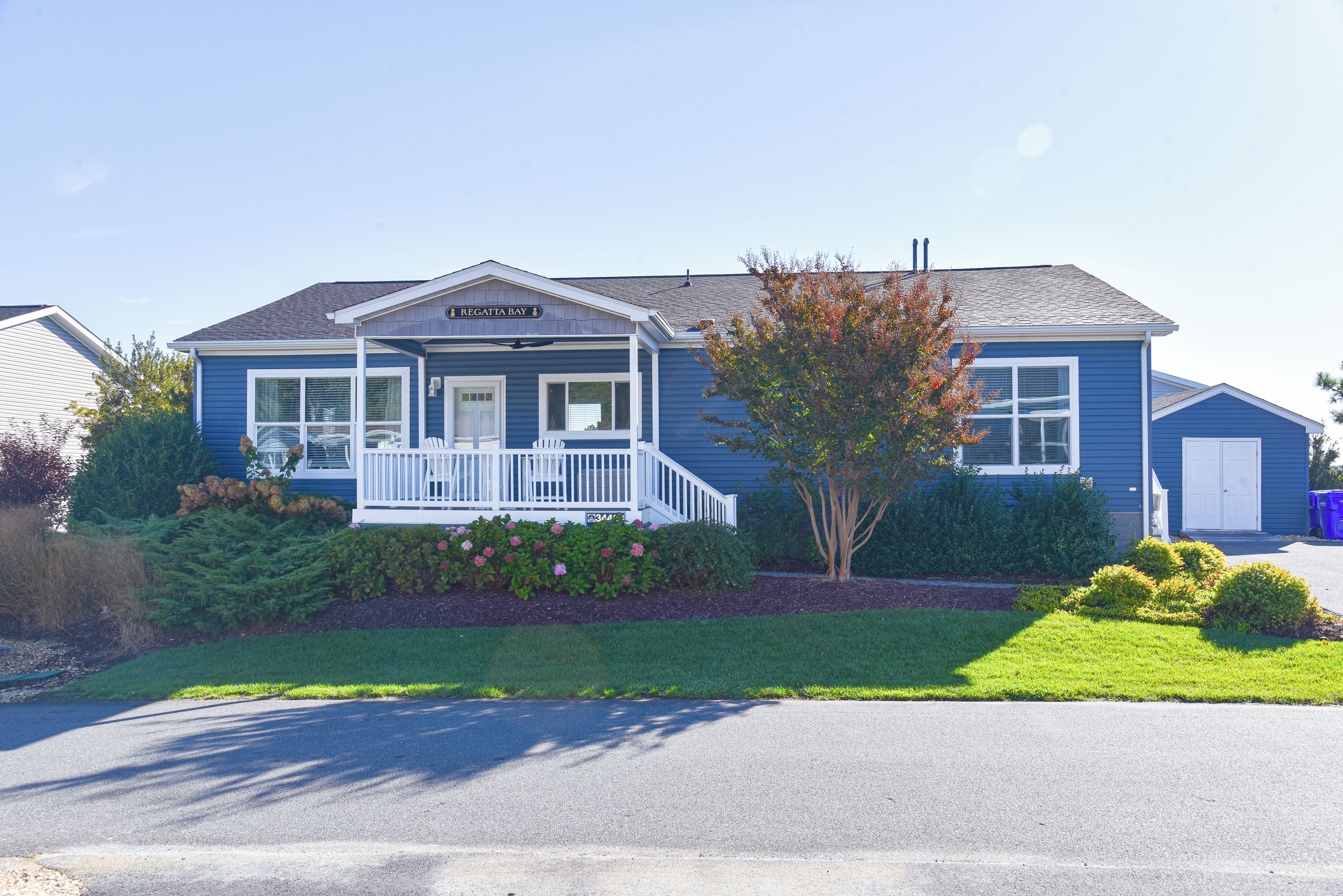 A two-story blue house with a porch, a sign reading "Regatta Bay," and well-maintained landscaping.