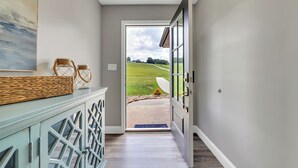 A hallway with a view of a green field through an open door.