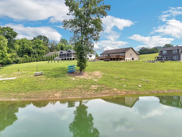 A residential area with a large grassy field, a small pond, and houses with a deck and outdoor seating. - Paradise Cove on Norris Lake w/ Kayaks (Maynardville)