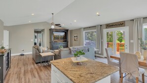 A modern kitchen with granite countertops, a dining area with a view, and a living room with a ceiling fan.