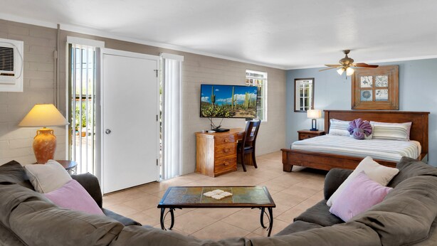A bedroom with a bed, a desk, a chair, a sofa, and a table. - Tucson Desert Rendezvous (Tucson)