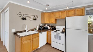 A kitchen with wooden cabinets, a white refrigerator, a stove, and a microwave. - Tucson Desert Rendezvous (Tucson)