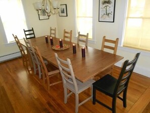 A dining room with a wooden table and chairs, candles, and framed pictures on the walls.
