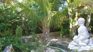 A garden with a statue, potted plants, and a small pond. - A Private Cottage Just Steps Away From the Beach and Hip Strip (Montego Bay)