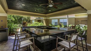 A spacious outdoor bar area with a large black bar, six high chairs, and a ceiling fan. - 3bed 2bath Luxury Yatch Club Condo at Aventura Fl, Parking Include! (Miami)