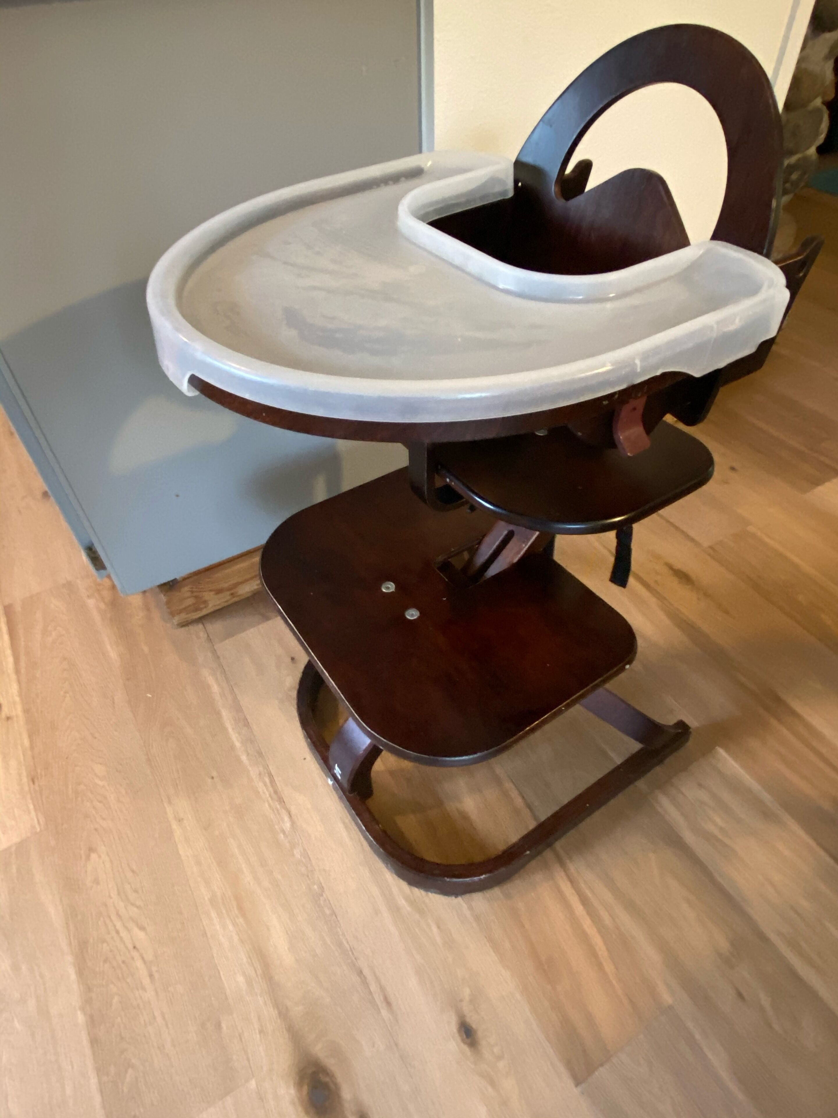 Una silla de madera con una bandeja blanca y respaldo curvo.