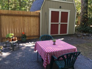A patio with a checkered tablecloth, two chairs, and potted plants.