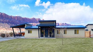 A modern house with a blue roof, a covered patio, and a mountain backdrop. - Beautiful Private Home W/ Large Living Spaces, Lots of Parking & Close to Trails (Moab)
