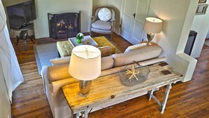 Ein gemütliches Wohnzimmer mit Kamin, Sofa, Couchtisch und Fernseher.