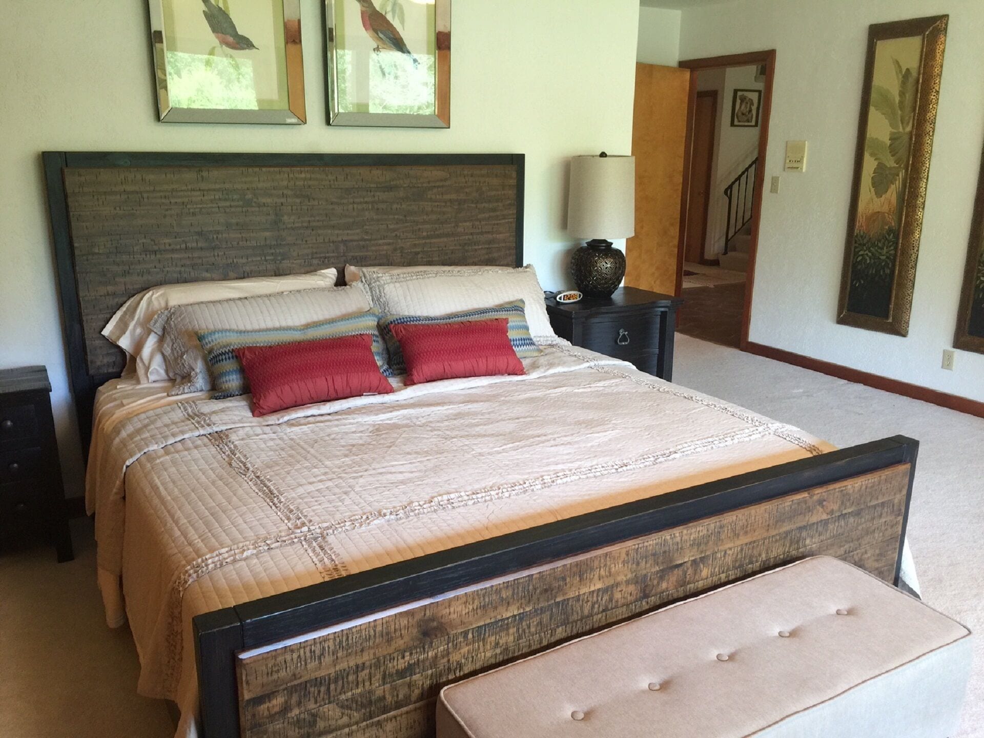 Un dormitorio con una cama grande, una mesita de noche, una lámpara y un banco.