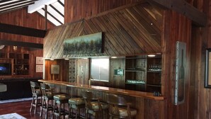 Un espace bar aux murs en bois, doté d’un plafond haut et d’un décor rustique.