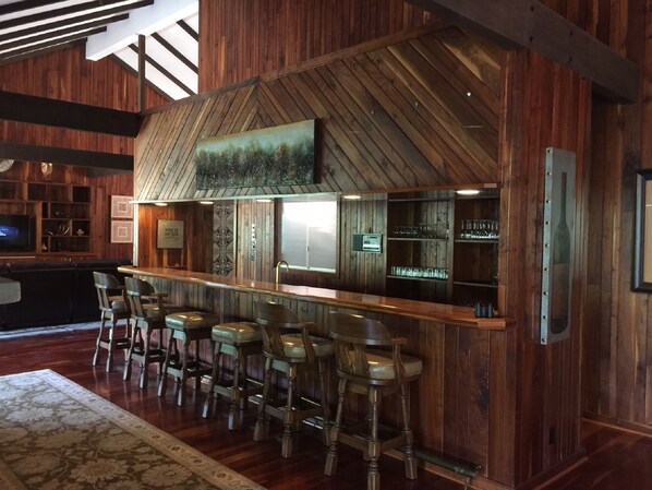 A bar area with wooden walls, a high ceiling, and a rustic design.