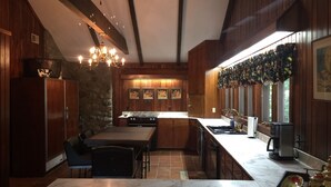 Une cuisine moderne avec un plan de travail en marbre, des armoires en bois et un mur en pierre.