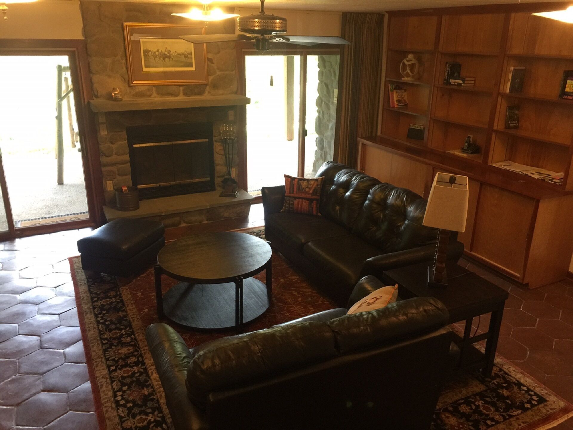 A living room with a stone fireplace, leather sofa, and a small round table.