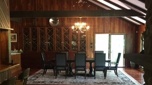 Un coin repas avec une table et des chaises en bois, un lustre et une grande fenêtre.