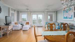 Ein geräumiges Wohnzimmer mit Essbereich, großen Fenstern und einem Deckenventilator.