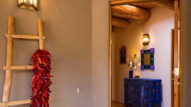 A wooden ladder leaning against a wall with a red tassel, a wooden ceiling, and a blue cabinet in the background.