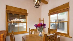 A dining area with a wooden table, chairs, and a vase of flowers.
