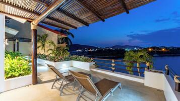 A terrace with a view of a body of water and city lights in the background.