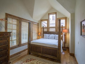 A bedroom with a wooden four-poster bed, a nightstand, a dresser, and a window with blinds. - Beautiful Penthouse-Summer Heated Pool, Slopeside!, Fireplace, 3 king beds (Telluride)
