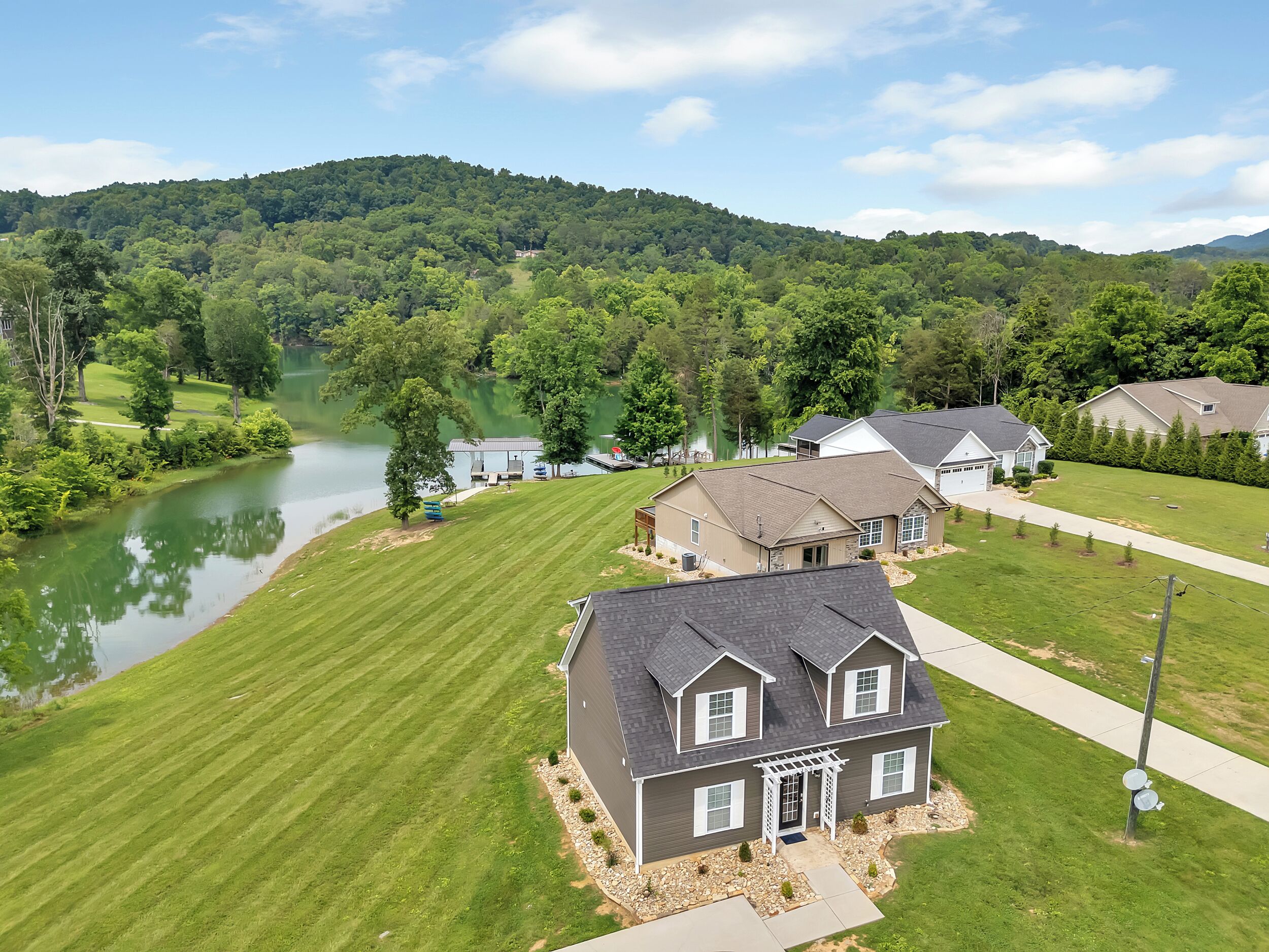 Un quartier résidentiel avec des maisons, un lac et une colline boisée.
