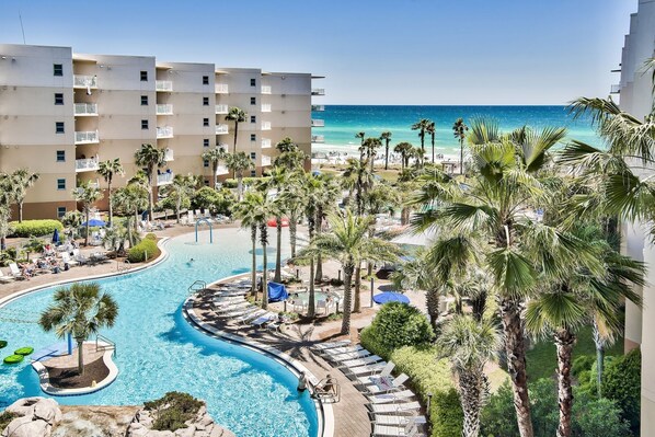 A resort with a pool, palm trees, and a beach view.