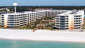 Un grand hôtel à plusieurs étages, doté d’une façade incurvée, situé juste à côté d’une plage.