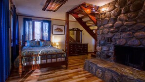 Ein Schlafzimmer mit einem hölzernen Bett, einem Steinkamin und einer Holztreppe.