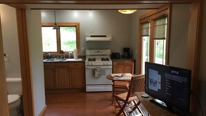 A kitchen with wooden cabinets, a stove, and a dining area with a table and chairs.
