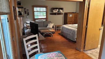 Une pièce de taille modeste comprenant un lit, un bureau, une chaise, une fenêtre avec des stores et une armoire en bois.