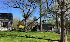 Ein Wohnhaus mit gepflegtem Rasen, einem Haus mit Veranda und einem kleinen Gartenhaus.