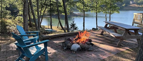 A lakeside patio with a fire pit, seating, and a view of the lake.