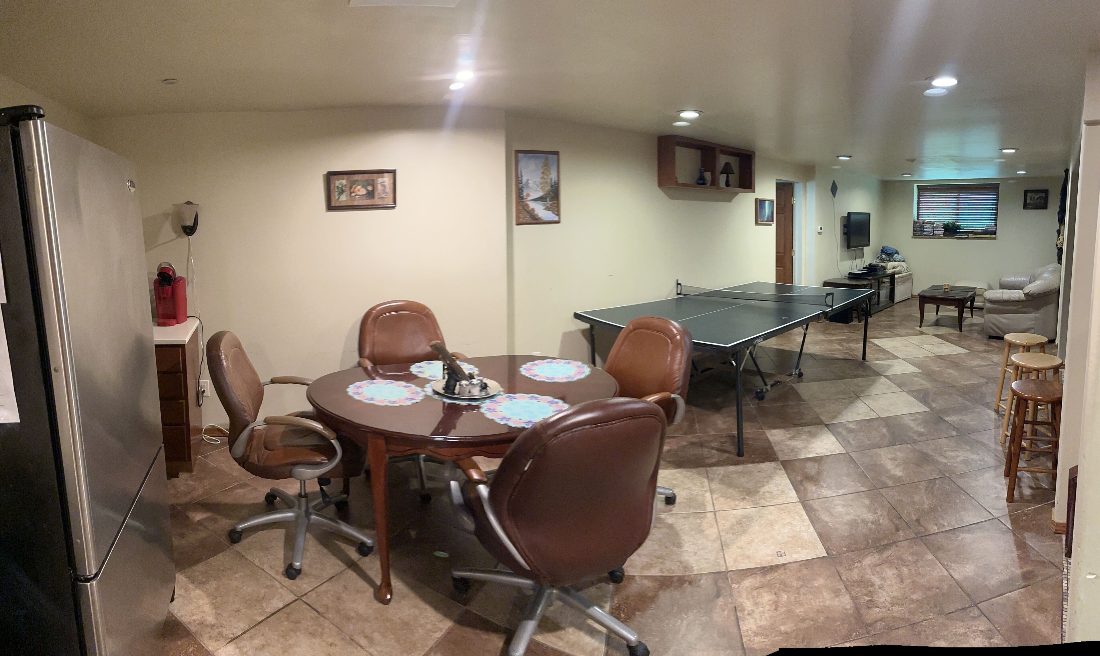 A conference room with a long table, chairs, and a television.