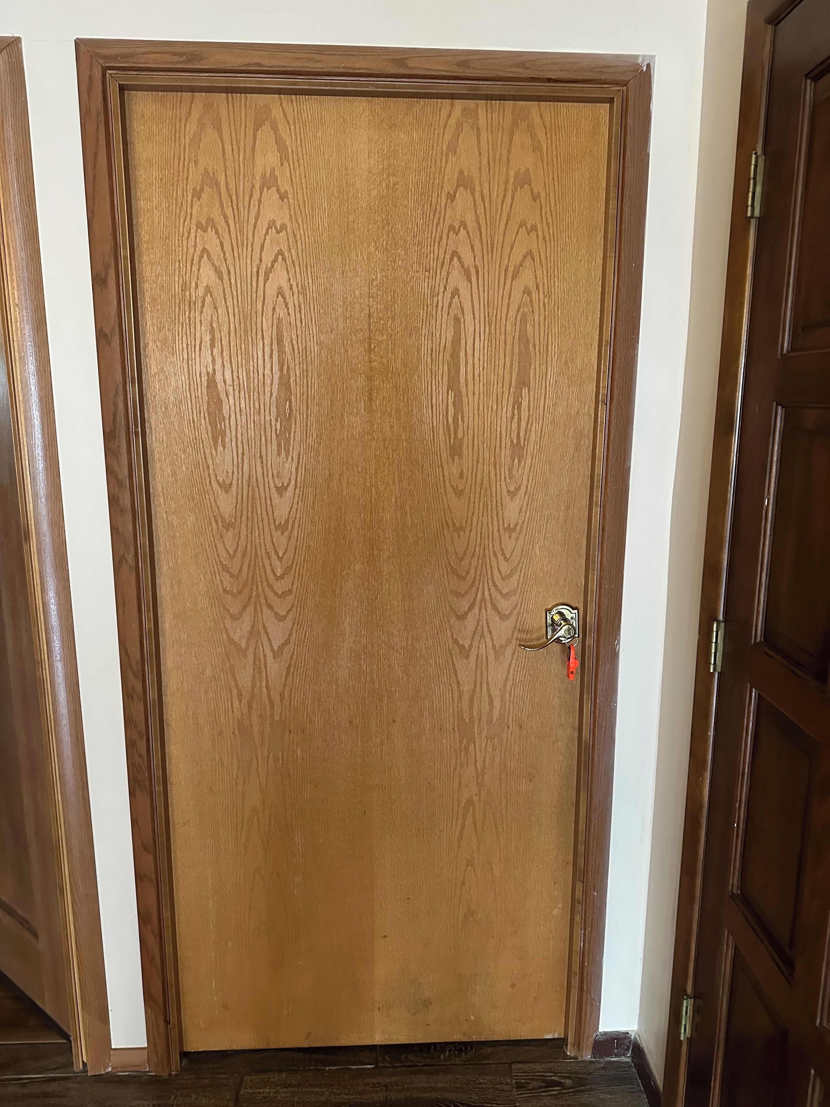 A wooden door with a keyhole and a red keychain.