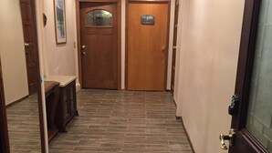 A hallway with wooden flooring and doors, one of which has a sign above it.