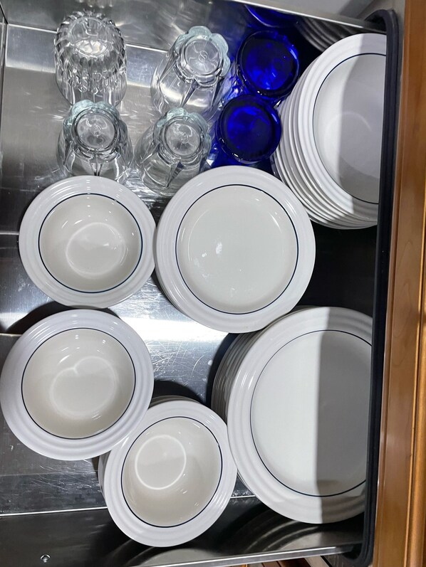Ein Tablett aus Edelstahl mit weißen Tellern und blauem Glas.