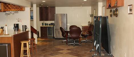 A compact kitchen with a refrigerator, coffee maker, and wooden stools.