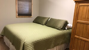 Un dormitorio con una cama, una ventana con persianas y un armario de madera.